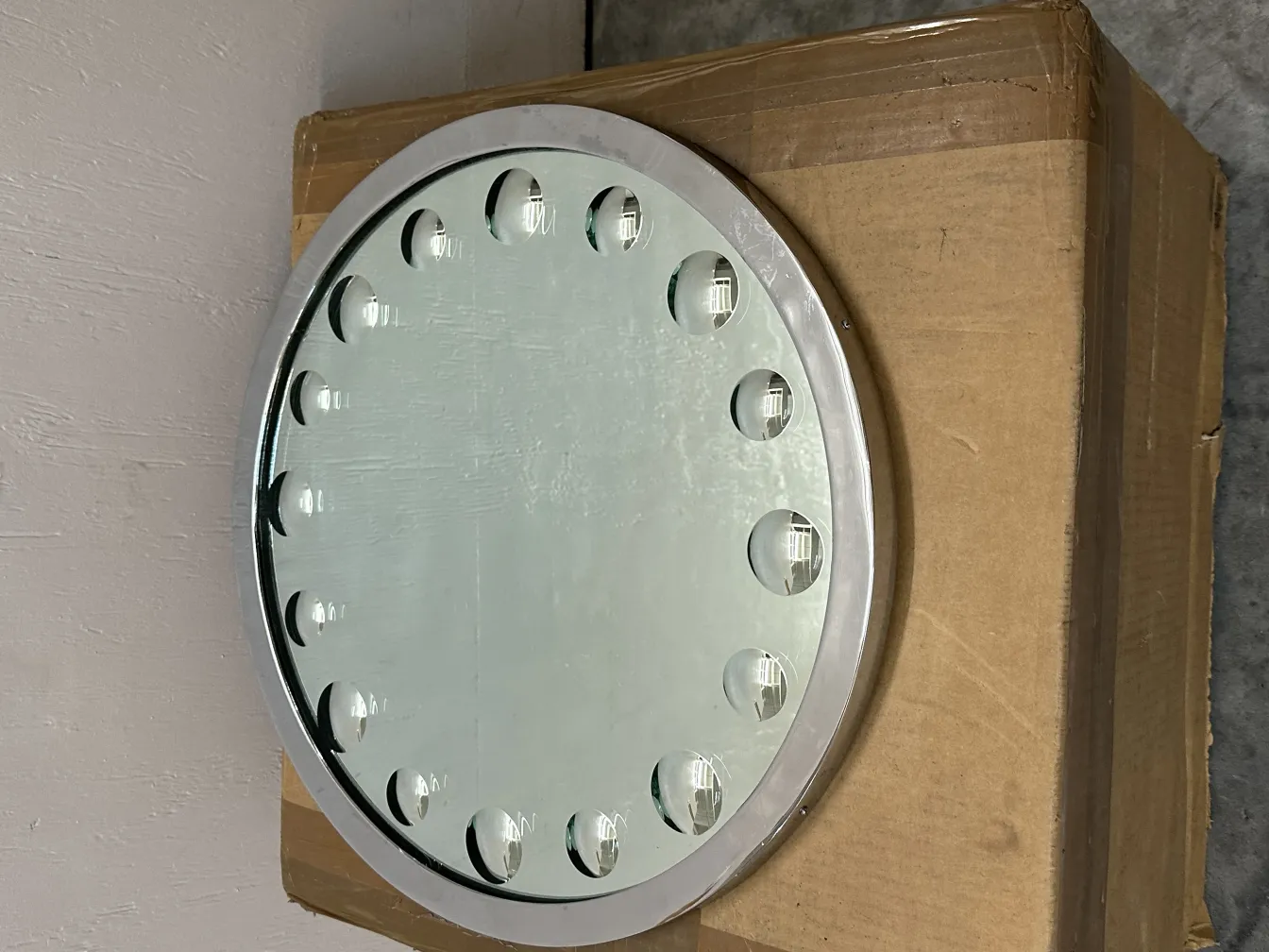 Specchio antico con una cornice decorativa e dettagli sottili. Osservato in un ambiente neutro.