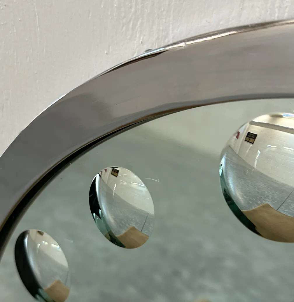 A set of two antique mirrors with rounded shapes in a neutral setting. Reflecting a bright environment.