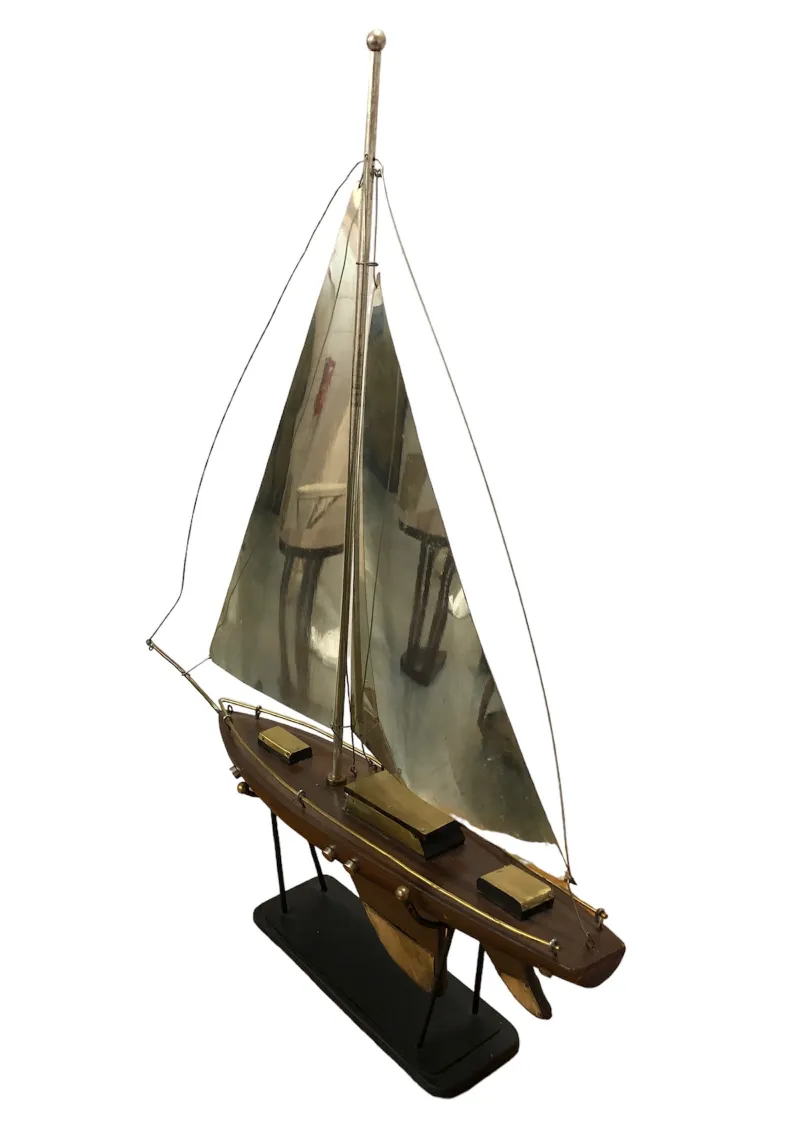 Modelo antiguo de barco con vela, detalles en metal y base.