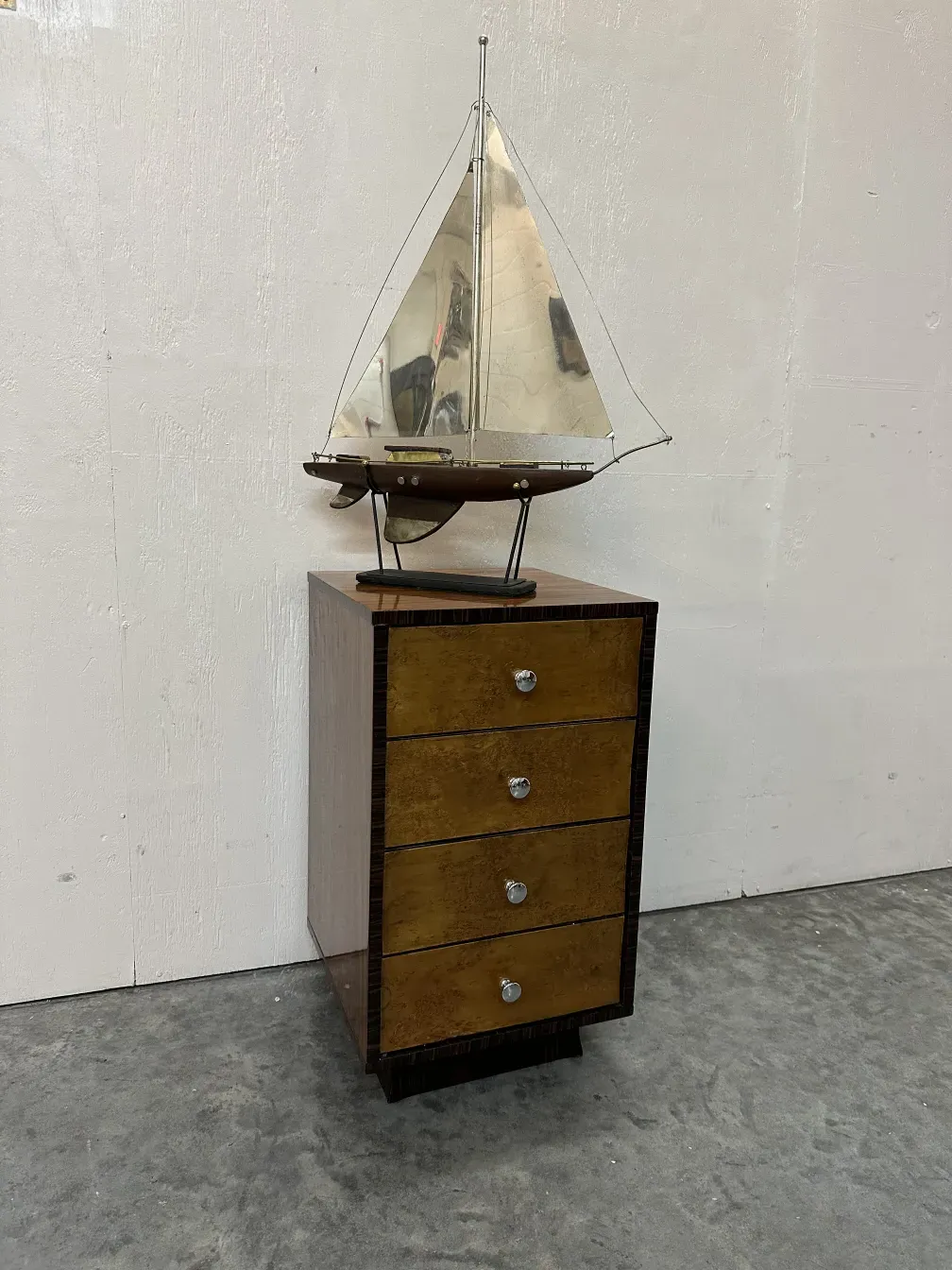 Bateau ancien décoratif avec armoire noire et voiles argentées.