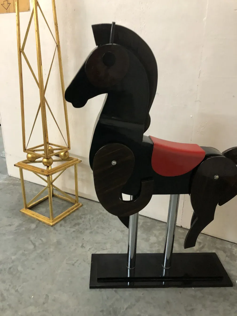 Jouet ancien de cheval noir avec une selle rouge.