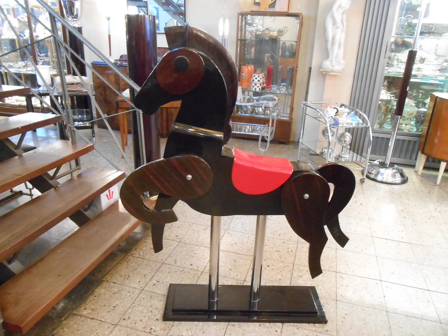 Cheval ancien de décoration avec selle rouge et base noire.