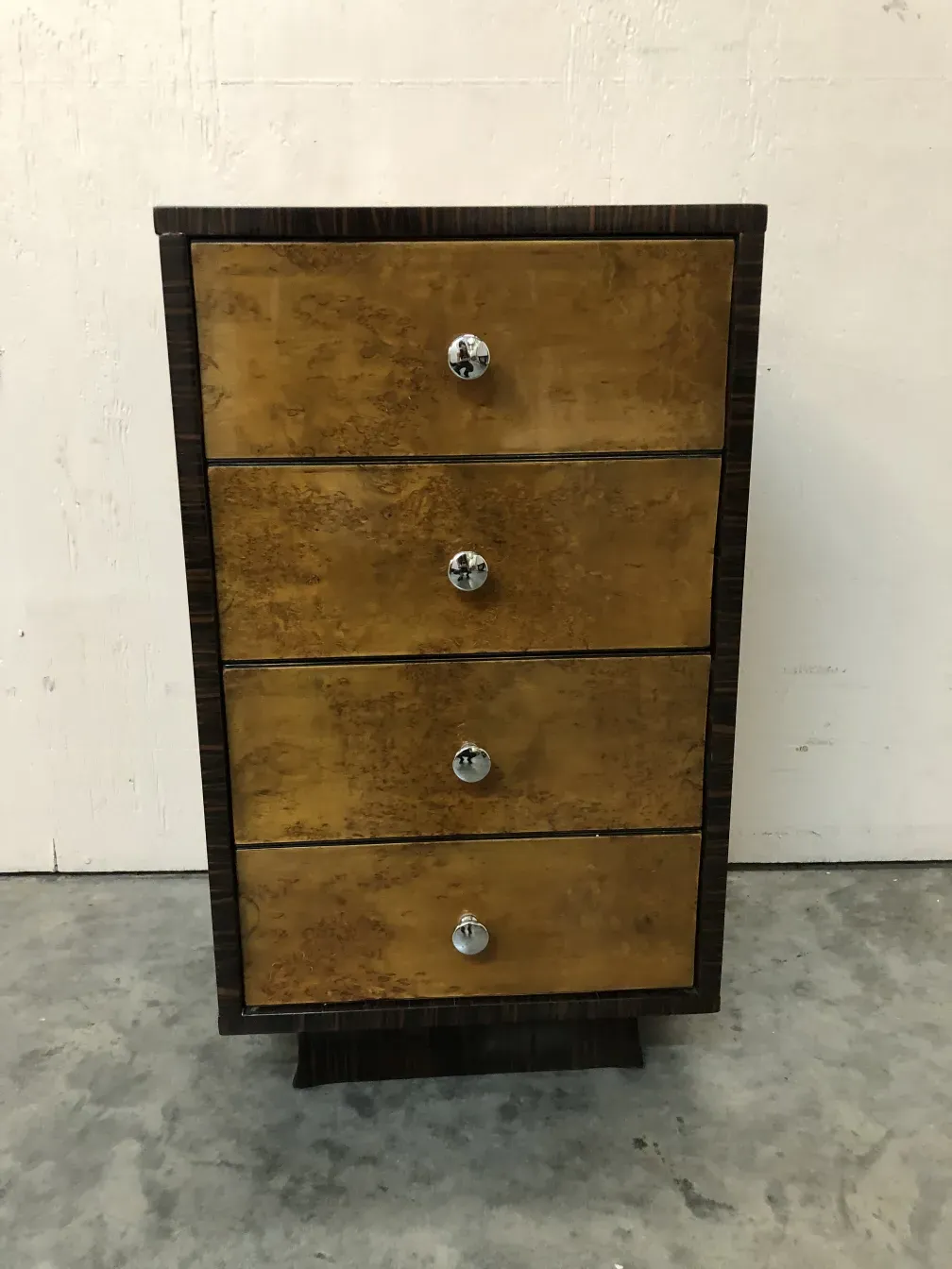 Commode ancienne avec quatre tiroirs et détails élégants dans un cadre simple.