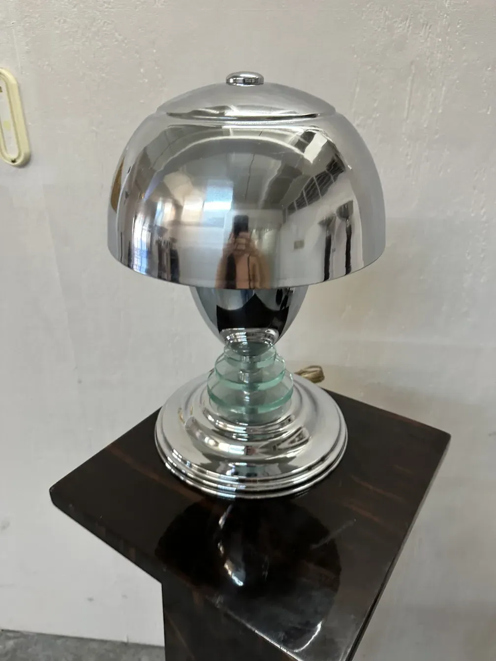 Antike Säule mit glänzendem Sockel und reflektierenden Details auf grauem Hintergrund.