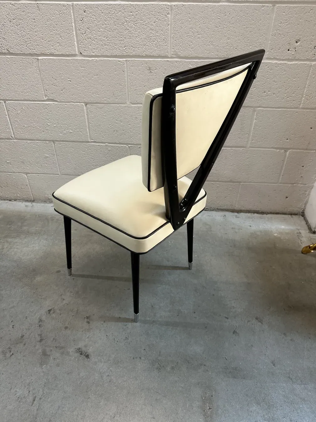 Vista laterale di 2 sedie antiche con design moderno di carlo mollino, su uno sfondo grigio.