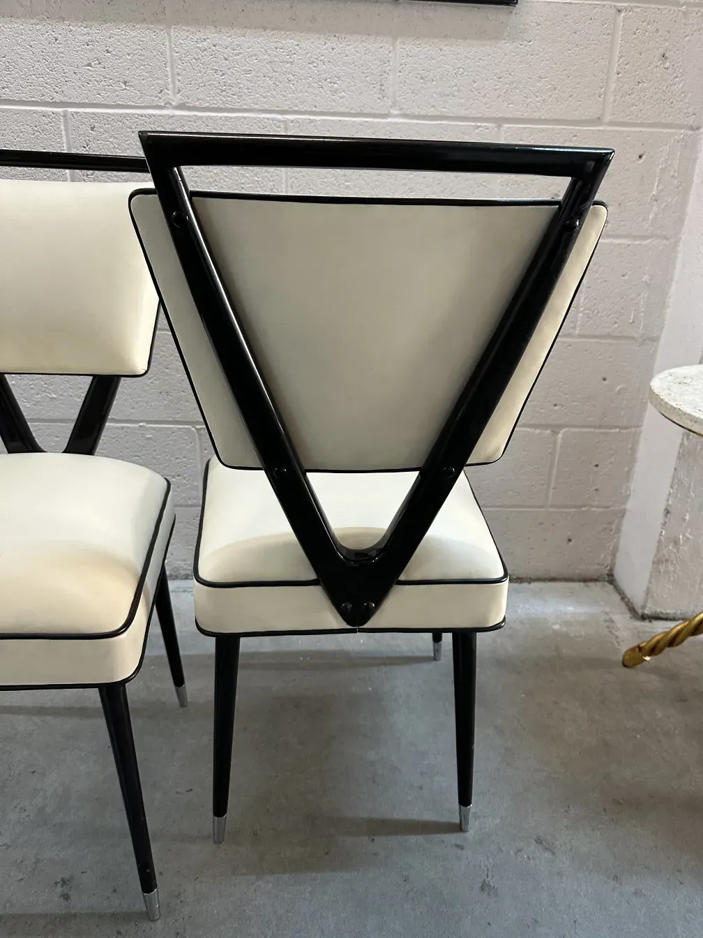 Vista de 2 cadeiras antigas com encosto em forma de V em um ambiente minimalista.