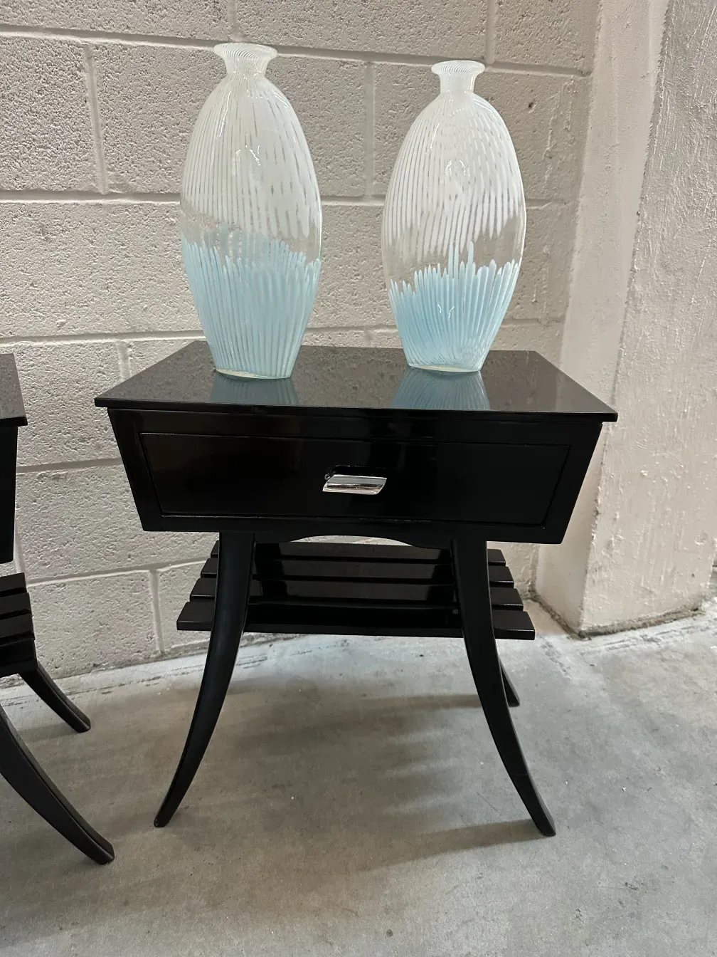 Mesa de luz antigua negra con dos jarrones decorativos en la parte superior.