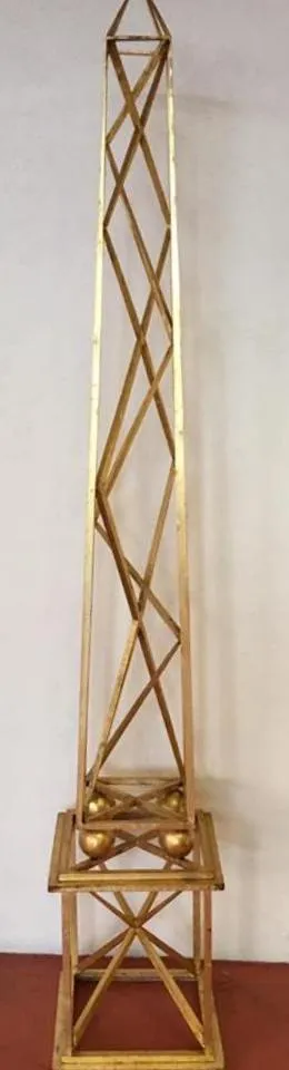 Dois obeliscos antigos dourados com um design decorativo na base.