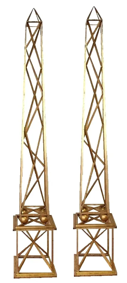 Descrição de dois obeliscos antigos decorativos, altos e elegantes. Destacam no ambiente decorativo.