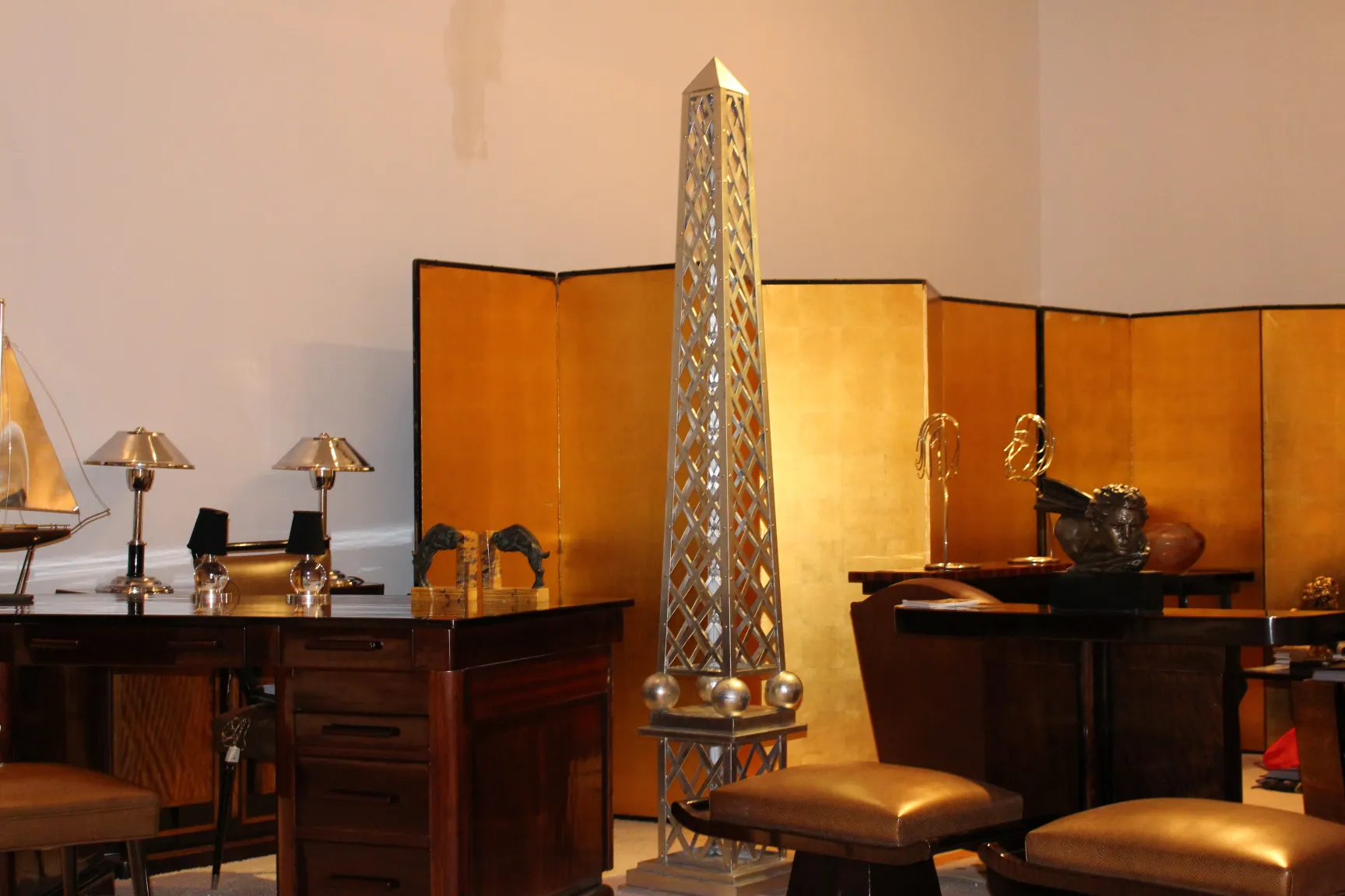 Antiker Obelisk mit elegantem Design vor goldenem Hintergrund.