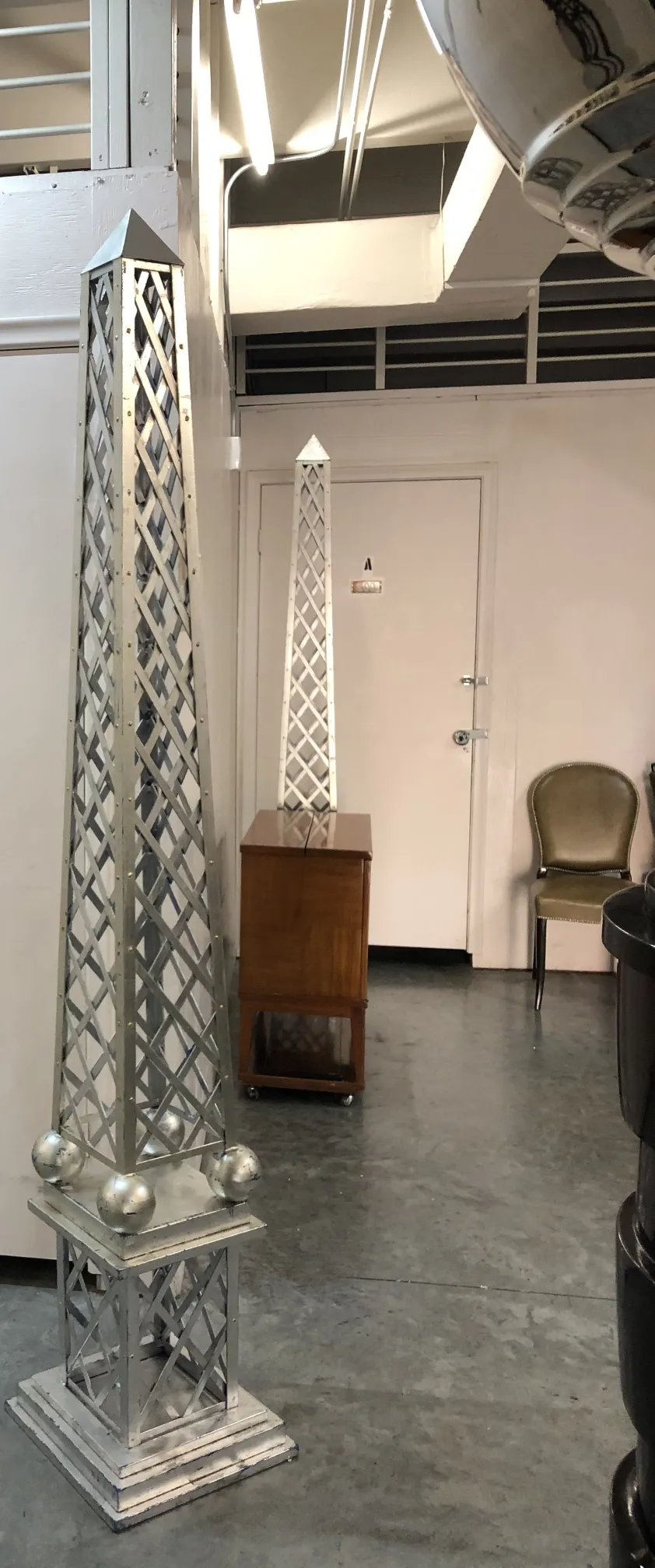 Obelisco antico con base decorativa e sfere metalliche, ambiente interno