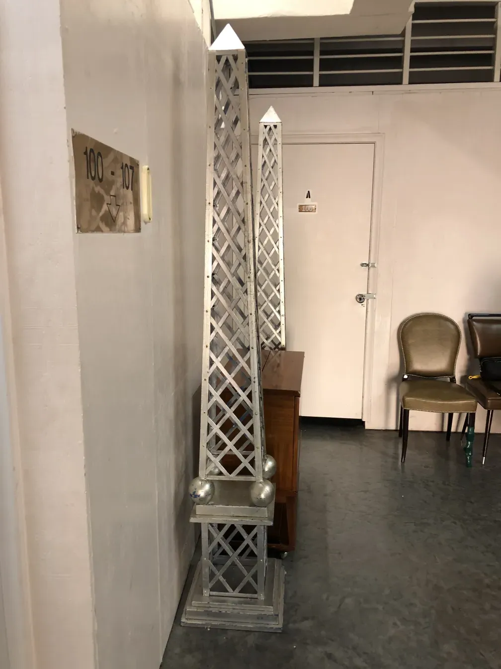 Antiguo obelisco en un ambiente interior, con sillas y una mesa.