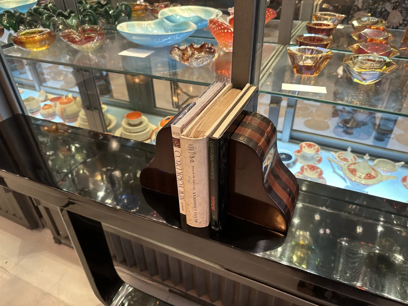 Fermalibri antichi e decorativi su una mensola di vetro con libri.