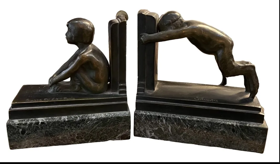 Suportes para livros antigos com figuras de crianças, uma sentada e uma em pé.