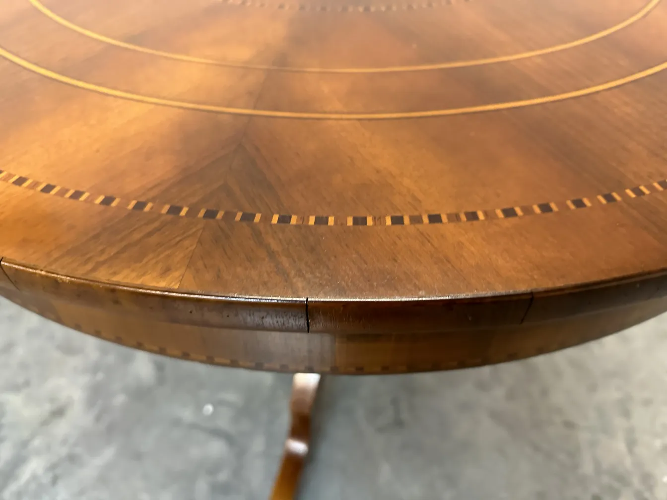 Tavolo antico rotondo con decorazioni sottili, ambiente elegante.