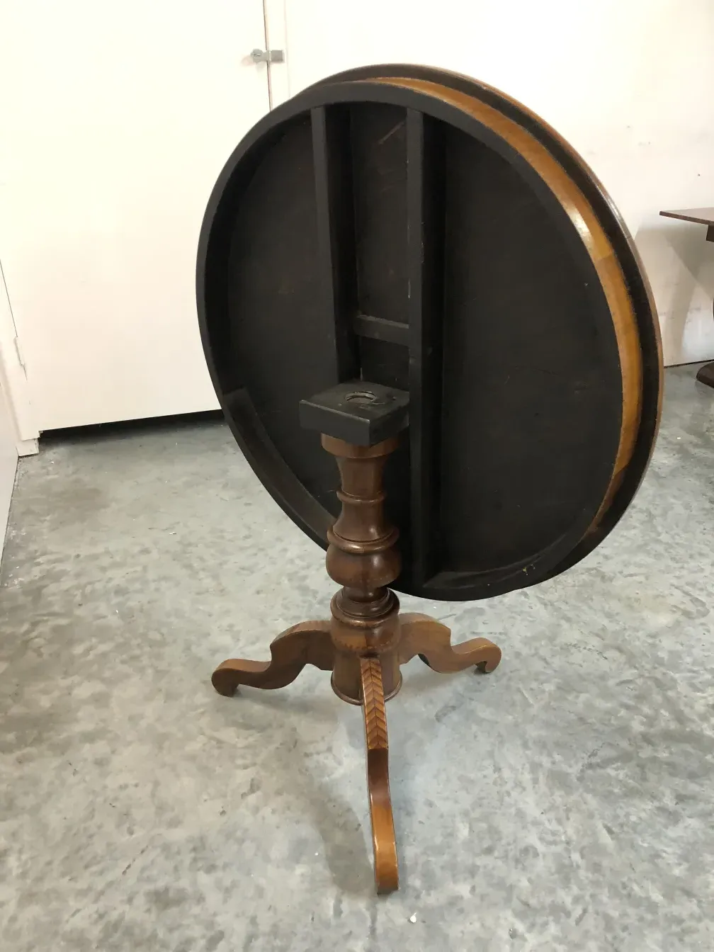 Antiker runder Tisch mit dekorativem Design und kunstvollen Beinen, in einem neutralen Umfeld platziert.