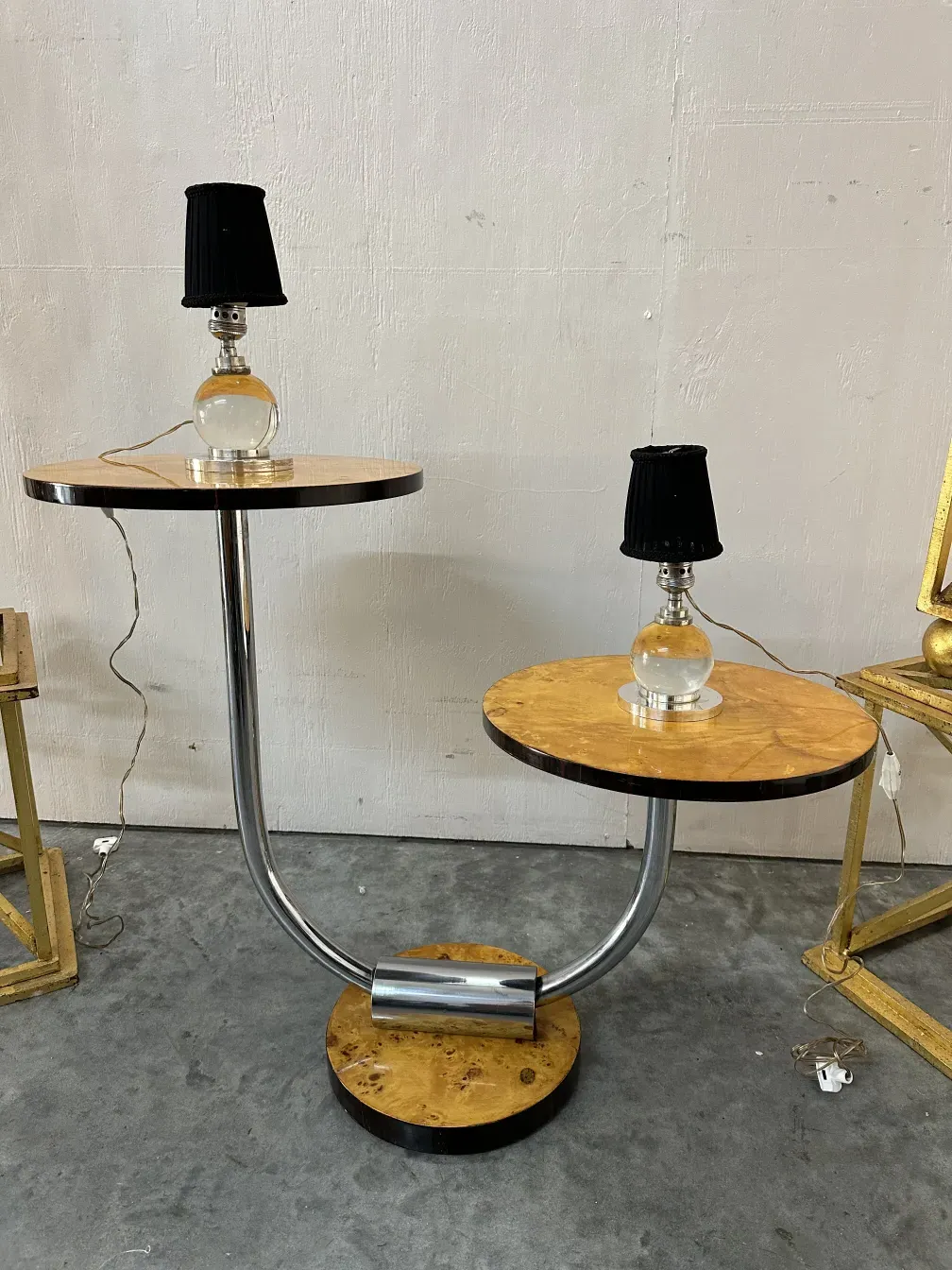 Deux lampes de table anciennes avec un design unique et des abat-jours noirs, complétées par une table courbée. Ambiance minimaliste.