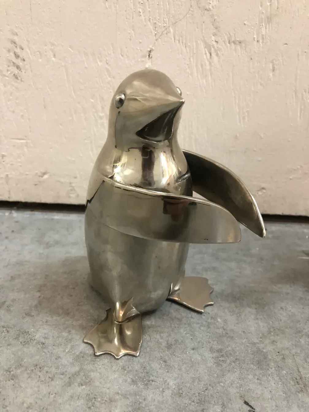 escultura antigua de 2 pingüinos en pie con detalles brillantes en un fondo neutro
