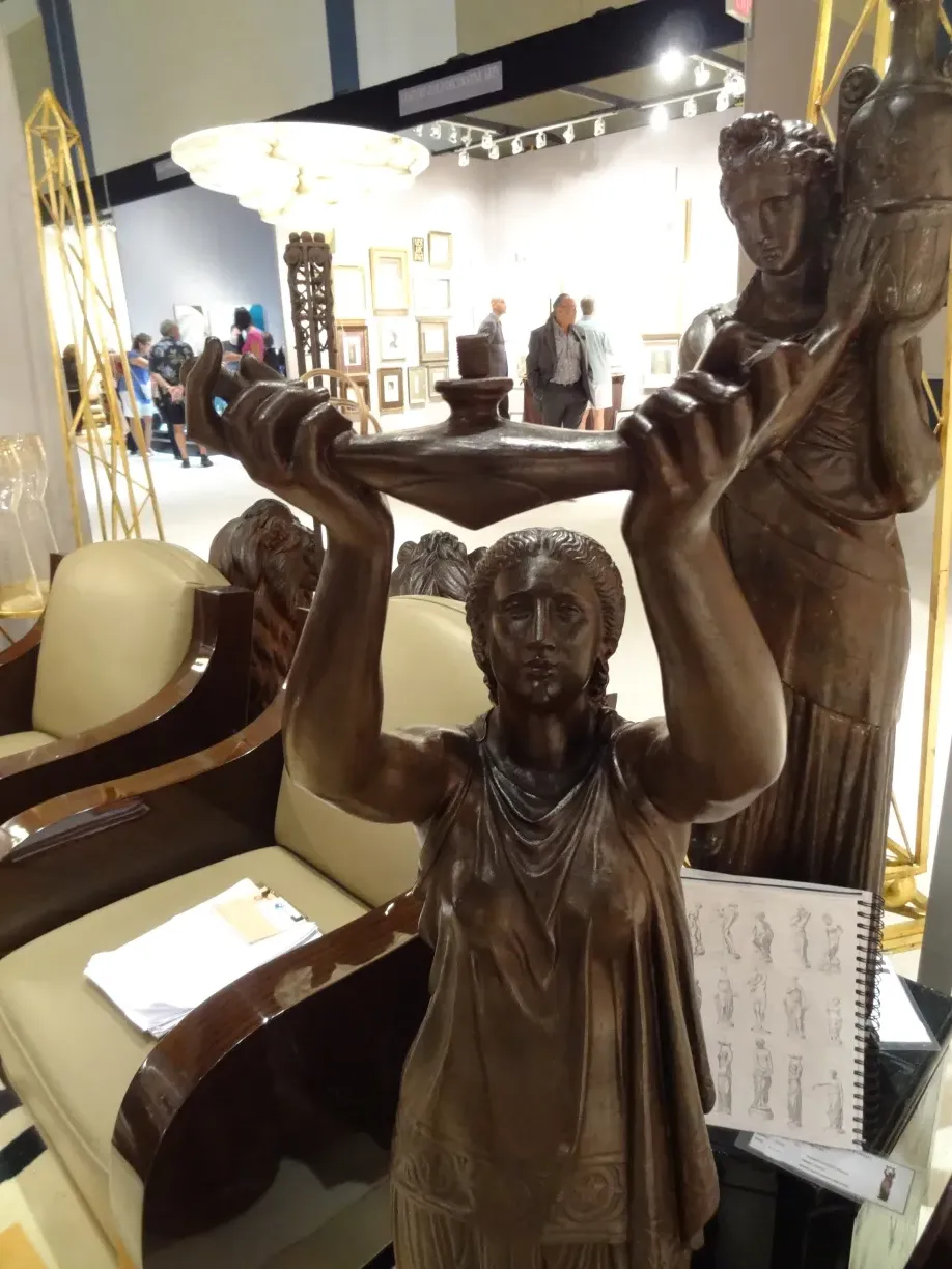 Escultura antiga com figura segurando um objeto, ambiente de exibição.