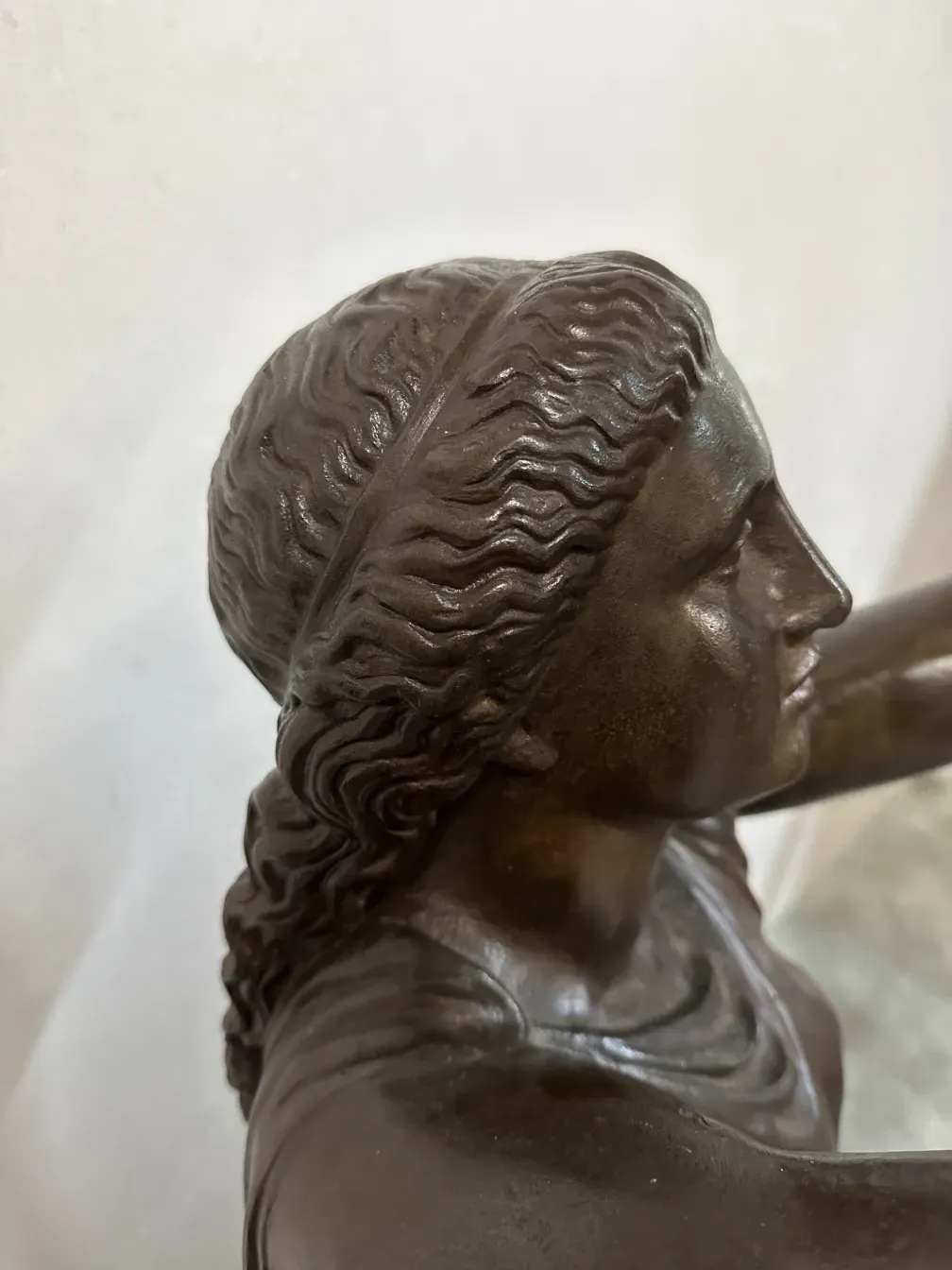 Detalle de la cabeza de una escultura antigua Val D´Osne con cabello ondulado.