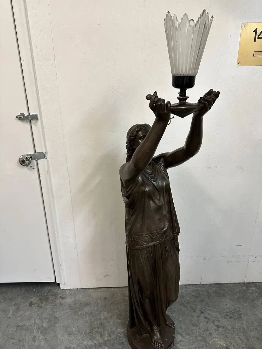 Antike Skulptur einer weiblichen Figur, die eine Lampe hält.