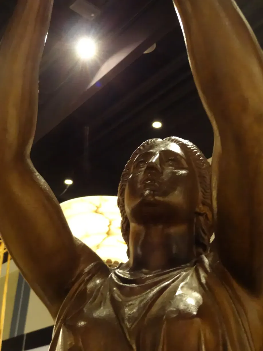 antike skulptur einer weiblichen figur mit erhobenen armen