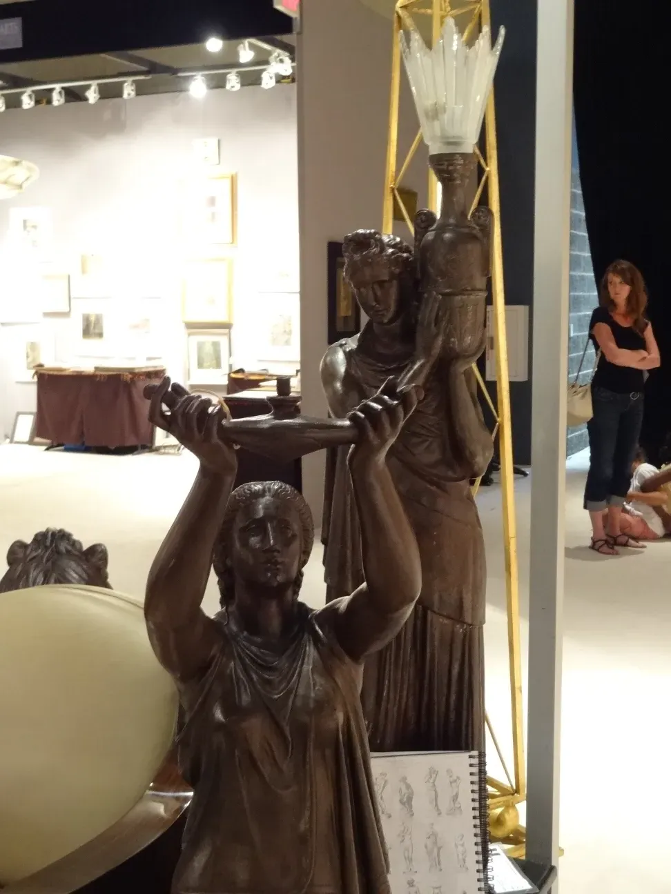 Antique sculpture showcasing fine details, relevant figures in the background.