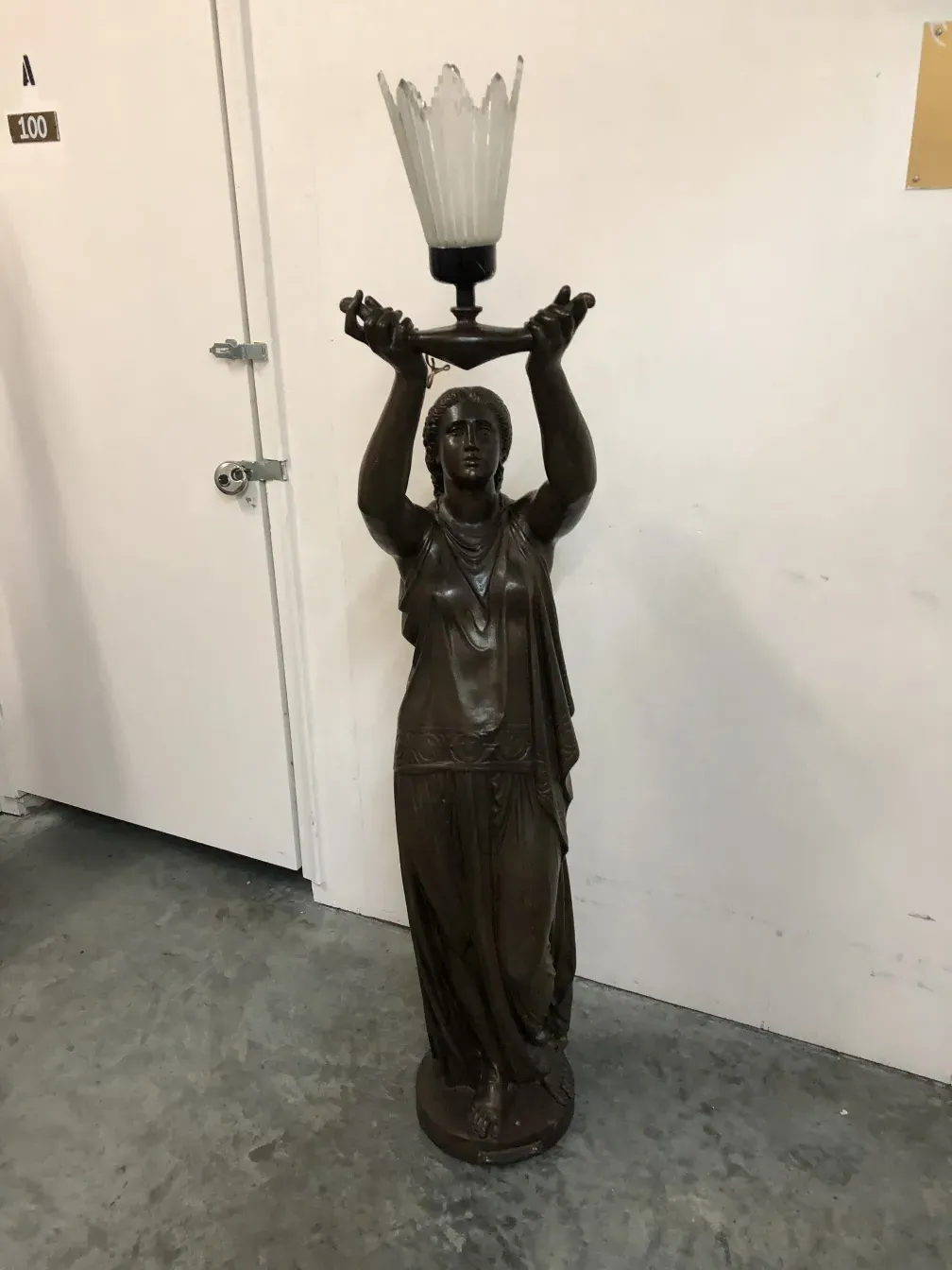 sculpture ancienne de Val D´Osne tenant une lampe avec lumière diffuse, détails sur le visage et les vêtements.