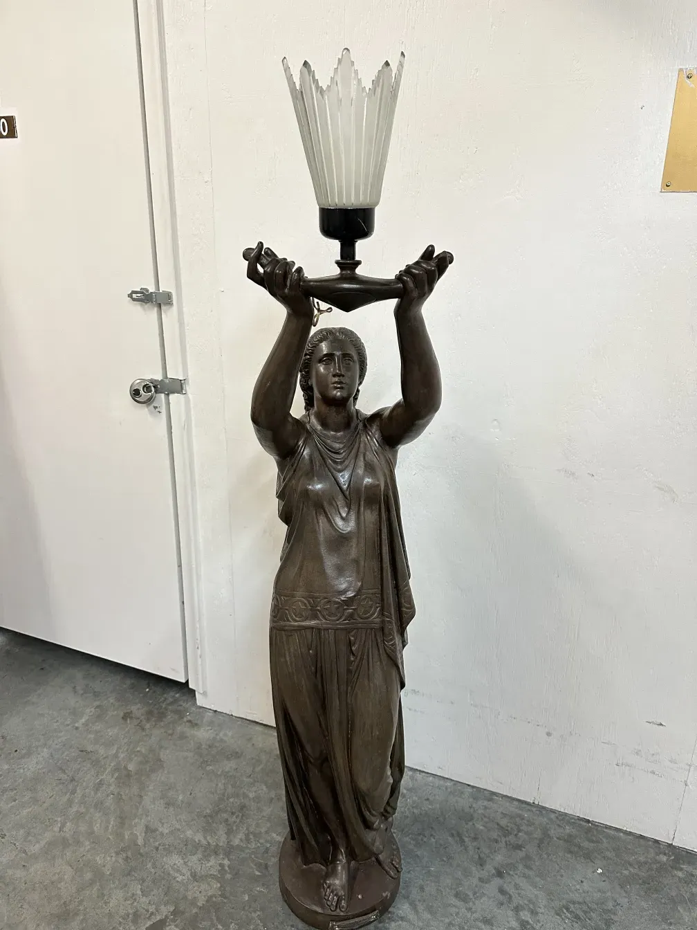 Antique sculpture from Val D´Osne featuring a female figure holding a lamp.