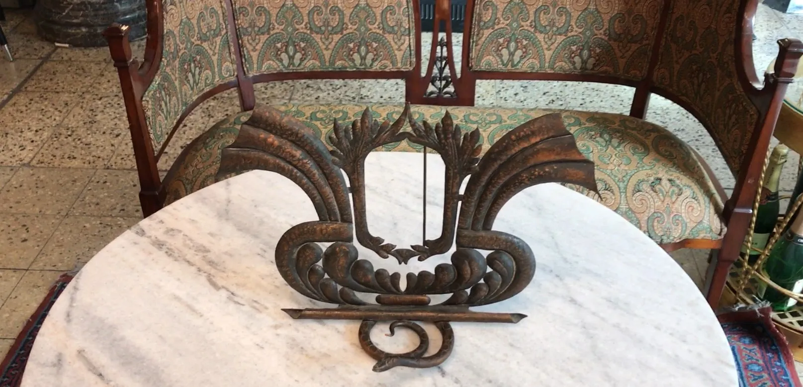 Antiker Bilderrahmen mit ausgefallenem Design und ornamentalen Details, platziert auf einem Marmortisch in einer eleganten Umgebung.