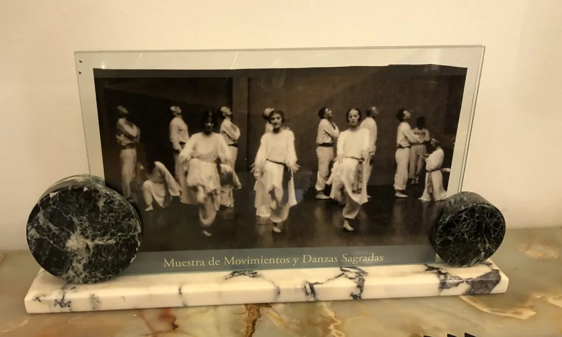 Porta-retrato antigo exibindo uma foto em preto e branco de dança, com decorações circulares.