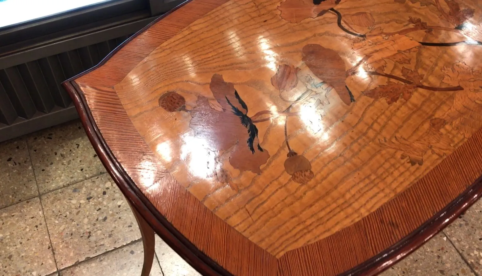 Table à manger antique d'Emile Gallé pour 2 personnes, ornée de motifs floraux. L'ambiance est chaleureuse.