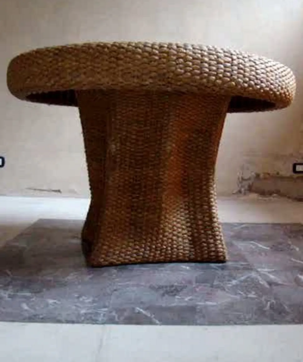 table à manger ancienne avec un design distinctif et un bord courbé, sur un fond minimaliste