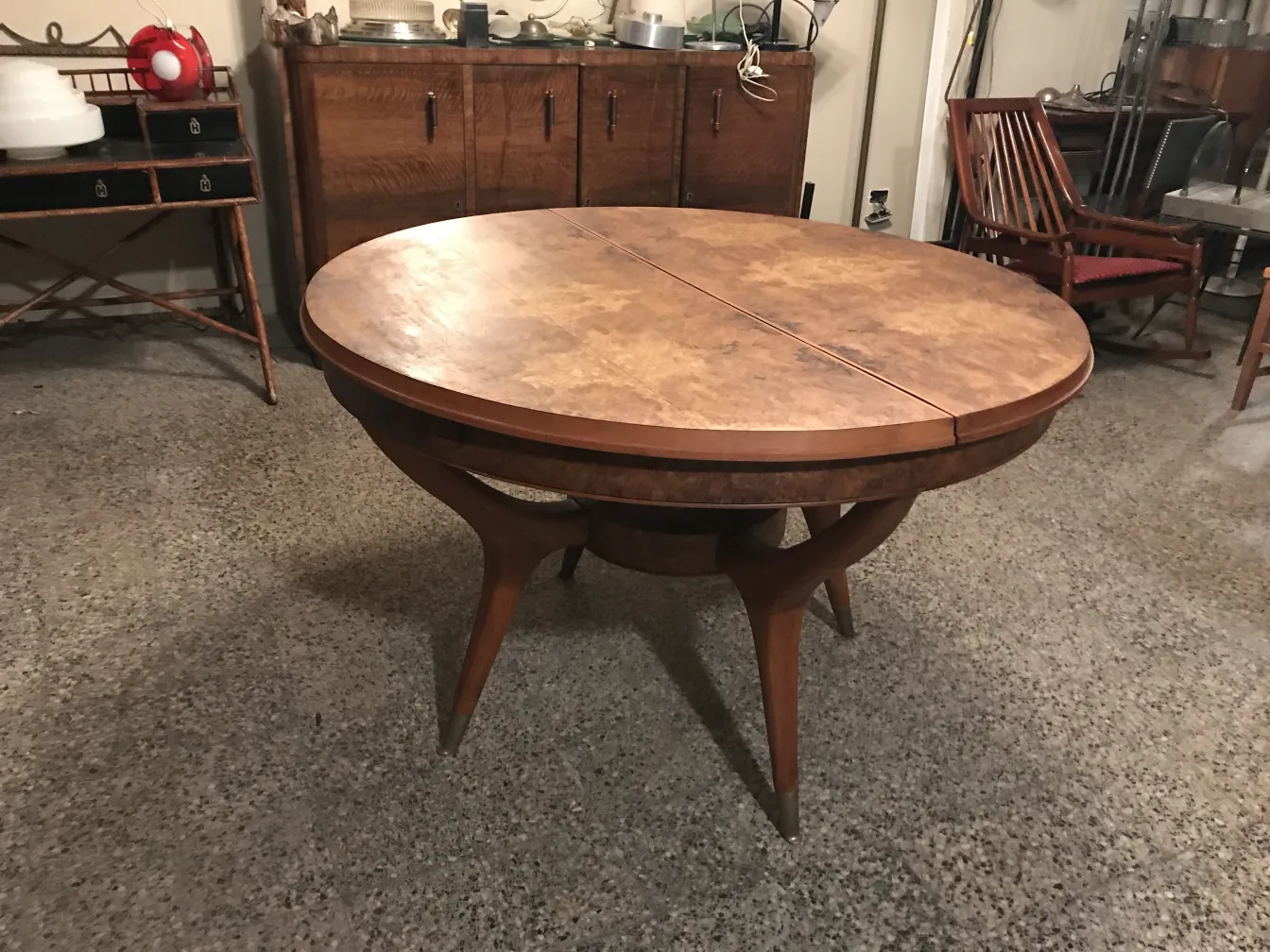 Mesa de comedor antigua con diseño circular y patas estilizadas en un ambiente acogedor.