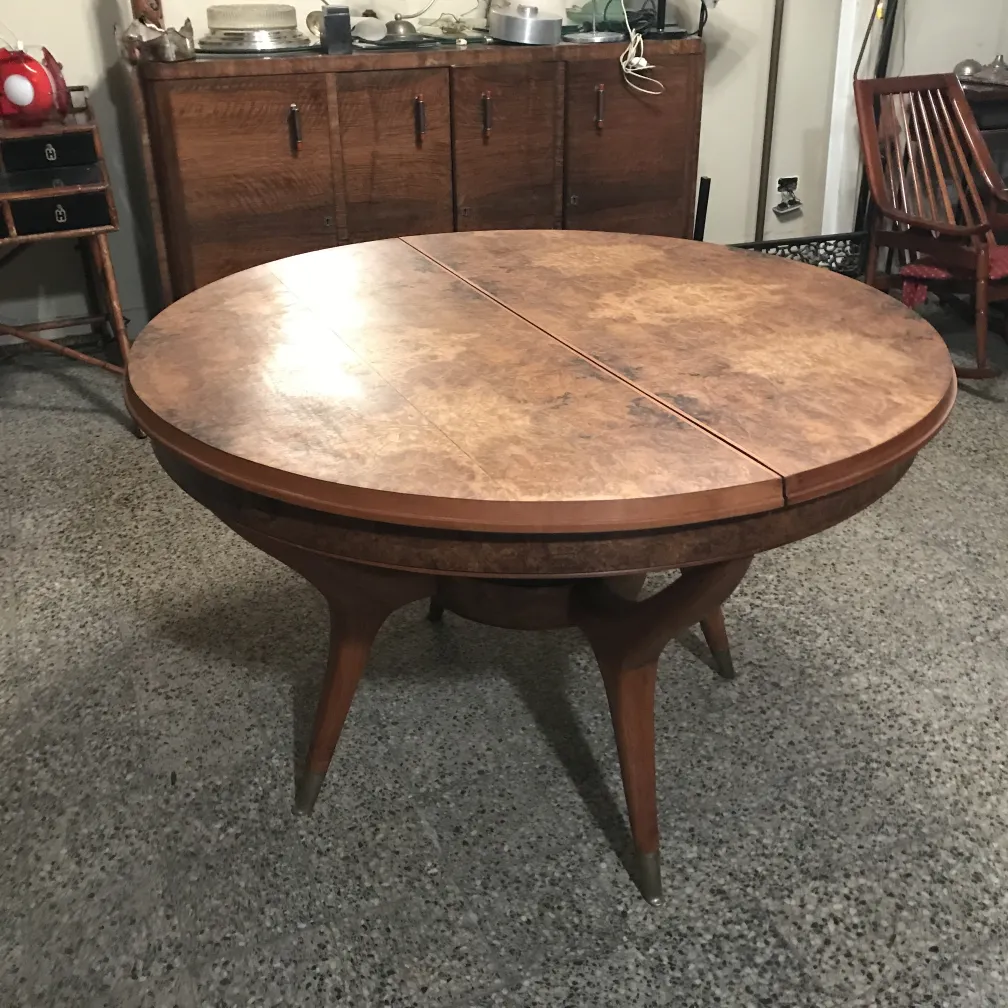 Mesa de jantar antiga, com tampo redondo e pernas elegantes. Ambiente acolhedor com itens decorativos.