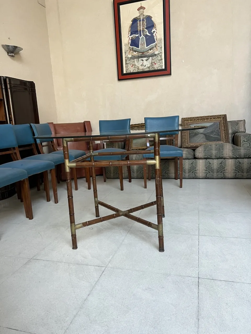 खाने की मेज़ प्राचीन, 6 लोगों के लिए आरामदायक सेटिंग में, नीली कुर्सियों और दीवारों पर कला के साथ सजाई गई।