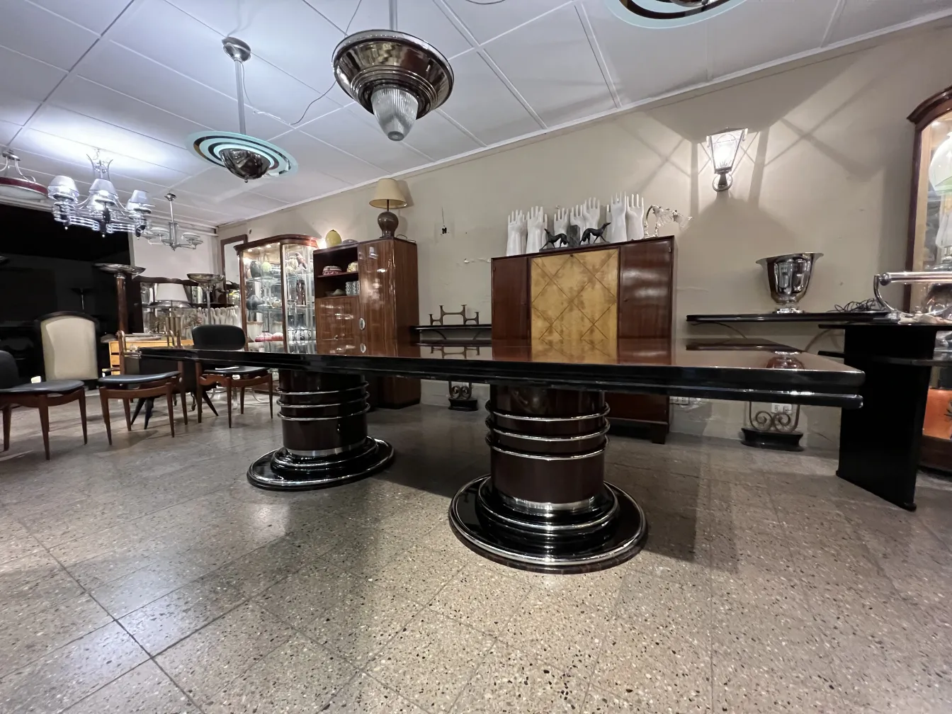 Mesa de comedor antigua para 14 personas en un entorno elegante con lámparas colgantes.