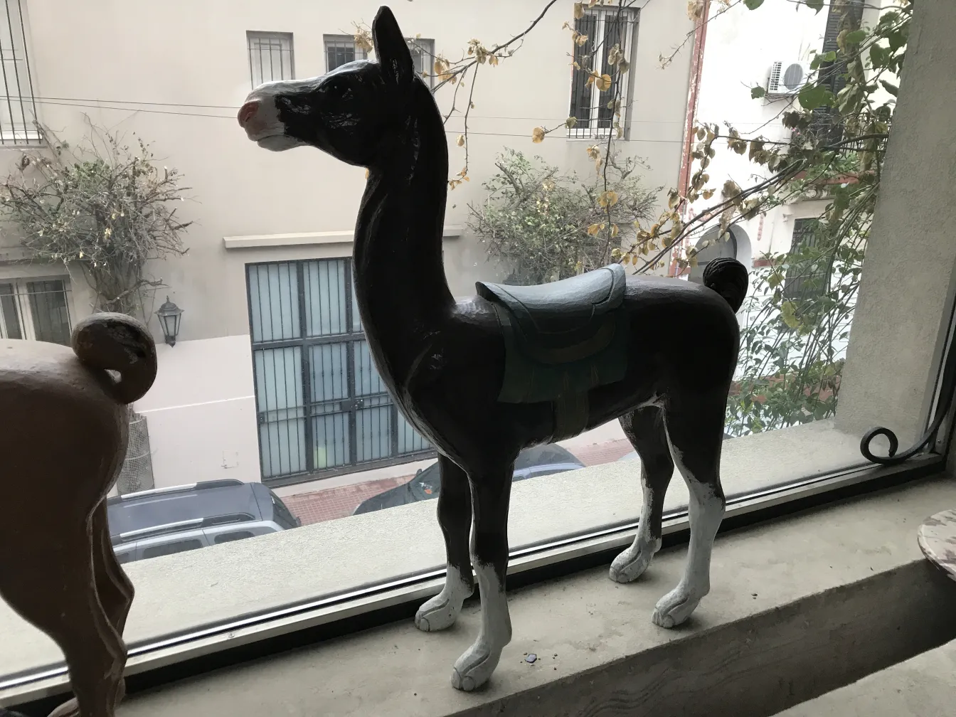 Llama antigua decorativa de cerámica, de pie en una ventana.