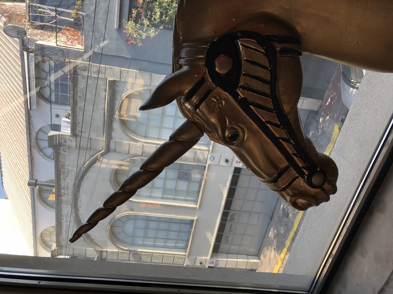 Cabeça de unicórnio dourado olhando pela janela