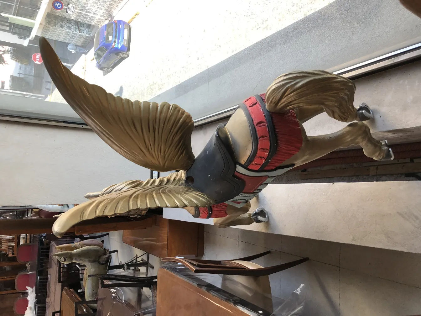 antike Einhornskulptur mit lebendigen Farben und gewölbten Flügeln, die einen Raum dekoriert