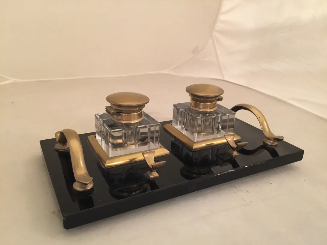 Tinteiro antigo com design de duas cabeças em uma base preta.