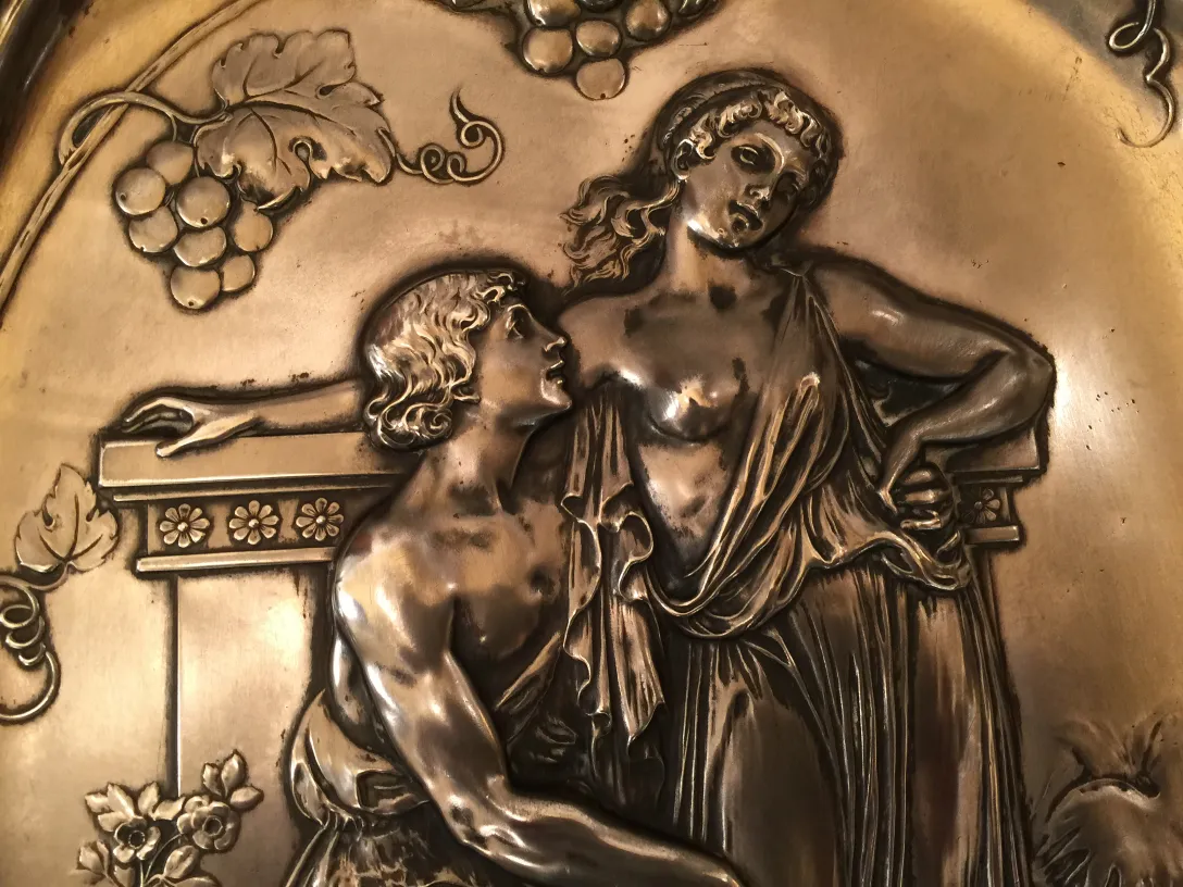 details of 2 antique wall plaques featuring figures and grapes