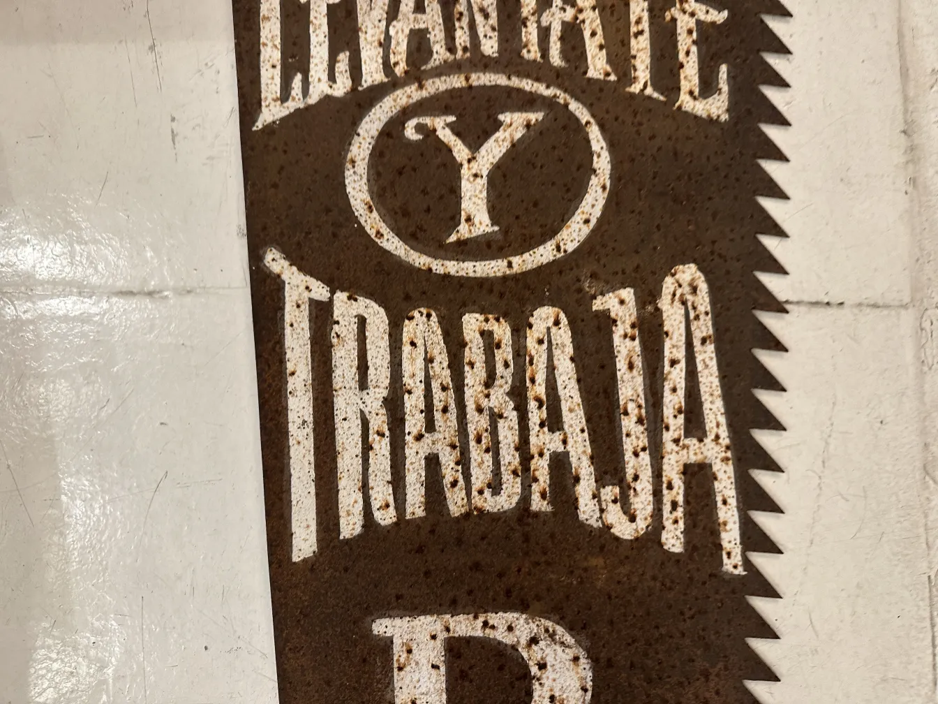 Sega pubblicitaria antica con iscrizioni visibili su sfondo arrugginito