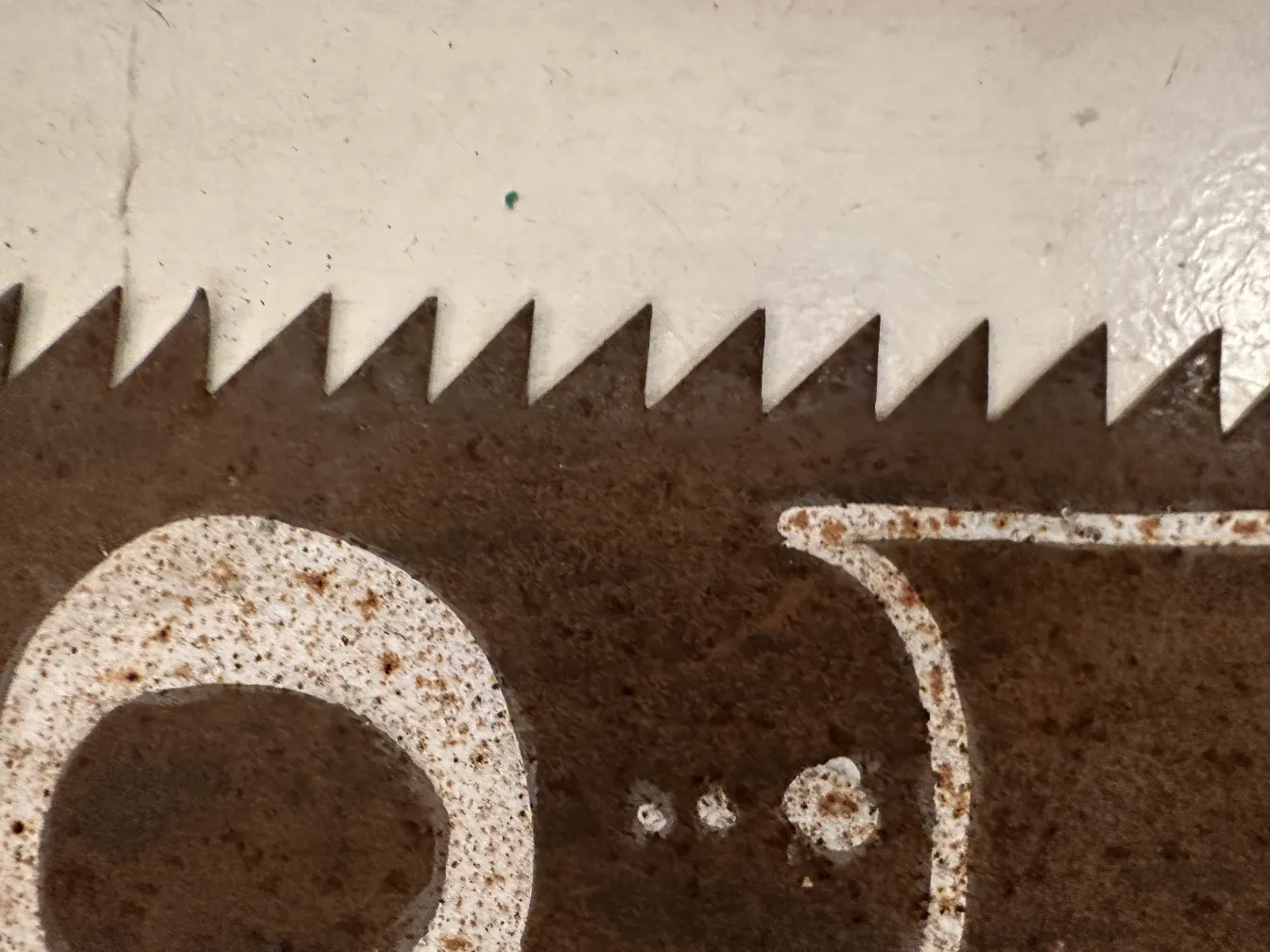 Scie de publicité avec des dents rouillées et des marques visibles, fond blanc.
