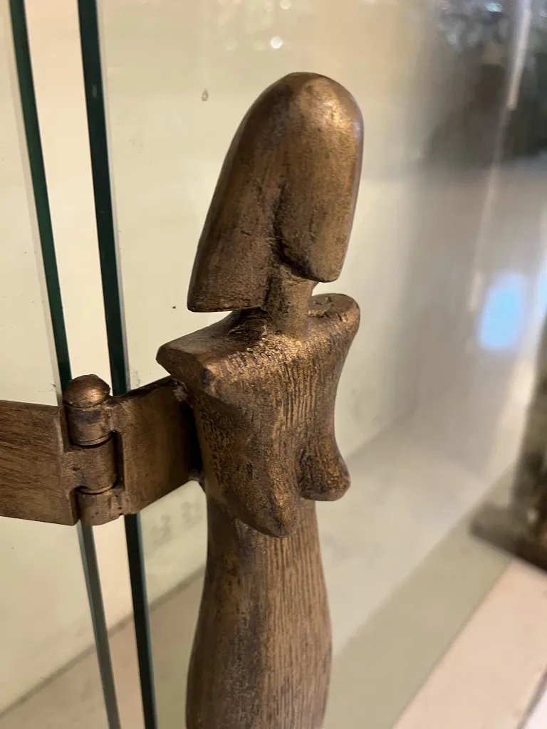 detalhe de frente de lareira antigo com forma estilizada de Alberto Giacometti e vidro