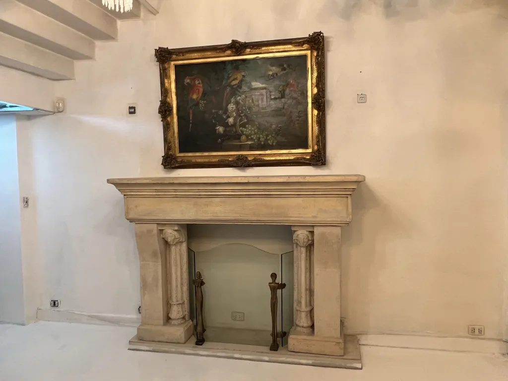 antique fireplace front with a landscape painting behind
