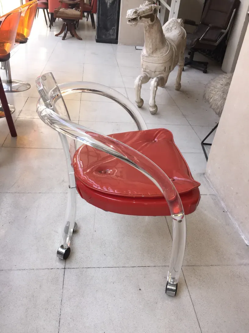 Quattro poltrone antiche rosse e trasparenti, decorando un ambiente elegante.