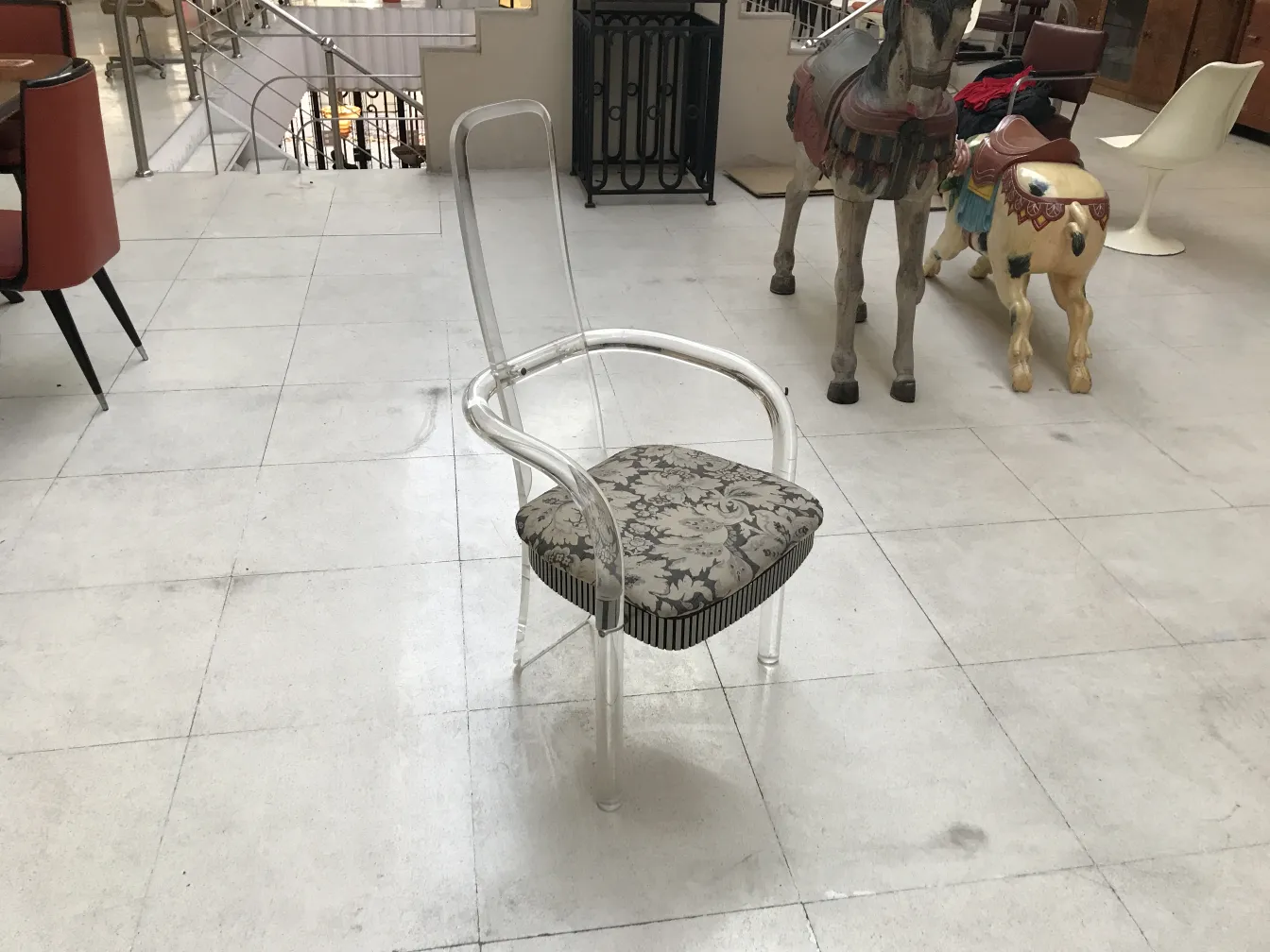 Four antique chairs and two armchairs in a neutral setting with decorative wooden horses.
