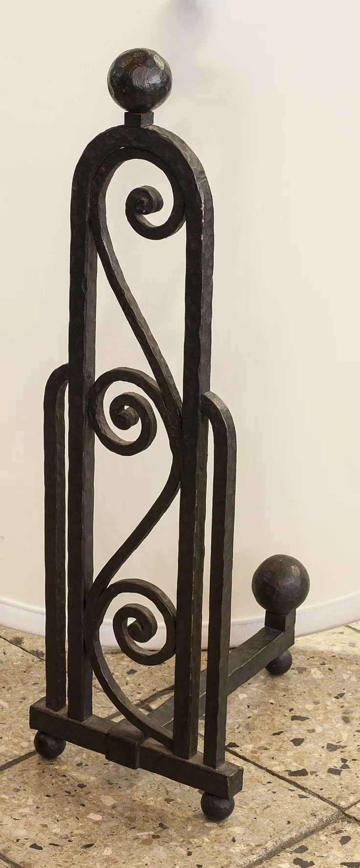 Antique iron andirons with decorative designs in a setting