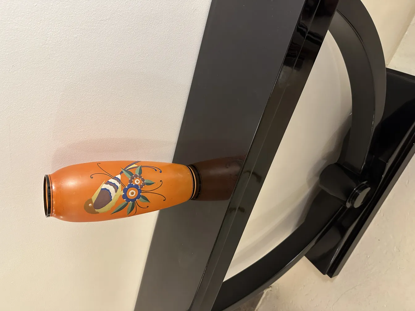 Florero antiguo decorativo colorido con diseño floral vibrante sobre fondo claro.